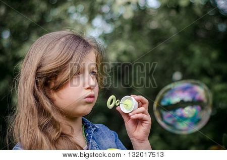 Portrait of cute lovely little girl blowing soap bubbles.