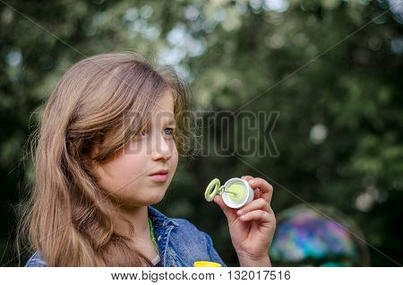Portrait of cute lovely little girl blowing soap bubbles.