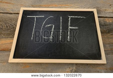 Thank god it's friday - TGIF - written in chalk on a chalkboard on a rustic background