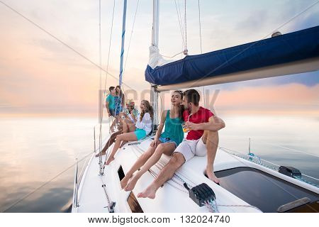 Young people sitting on yacht. Guys and girls laughing. Laughter prolongs life. Happy and healthy youth.