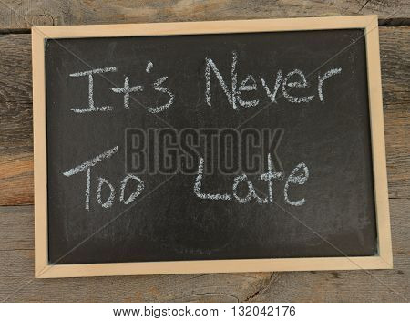 It's never too late written in chalk on a chalkboard on a rustic background