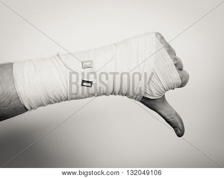 Bad news and information. Medicine aspects. Male hand with bandage showing thumb down sign symbol.