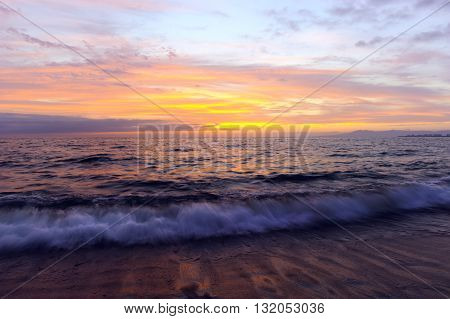 Ocean sunset is a brightly lit golden seascape with a gentle wave rolling to the shore.