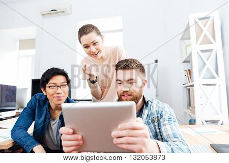 Three concentrated young businesspeople working with tablet together