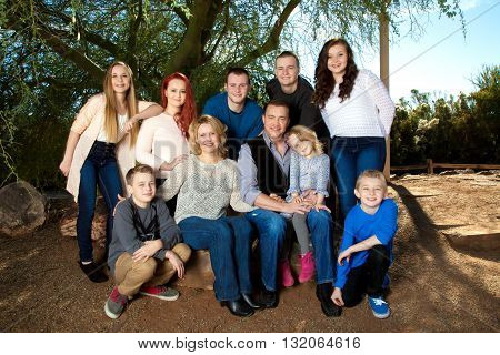 Portrait of a large family under a mesquite tree. They are close and connected.