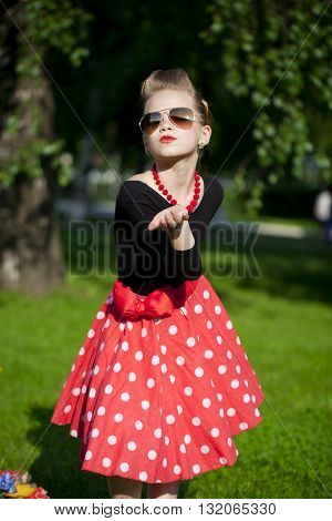 Pin-Up. Lovely little girl in the retro red dress in summer park