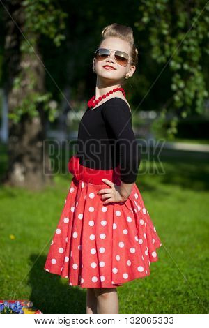 Pin-Up. Lovely little girl in the retro red dress in summer park
