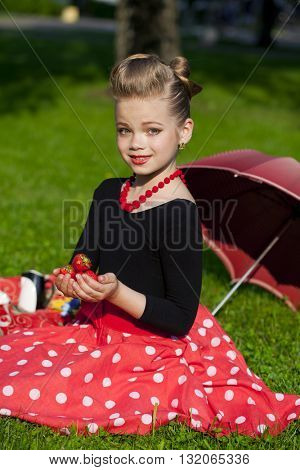Pin-Up. Lovely little girl in the retro red dress in summer park