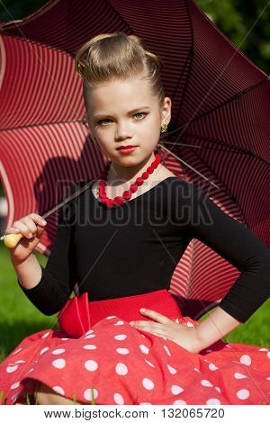 Pin-Up. Lovely little girl in the retro red dress in summer park