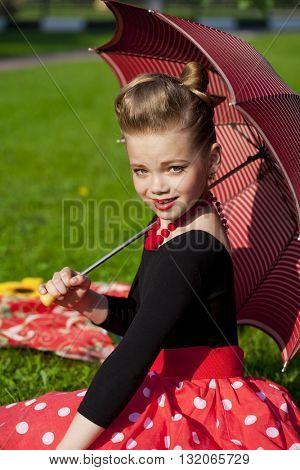 Pin-Up. Lovely little girl in the retro red dress in summer park