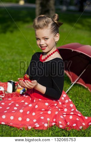 Pin-Up. Lovely little girl in the retro red dress in summer park
