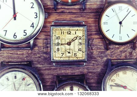 A selection of retro and antique watches over old wood background. Filtered to look like an aged instant photo.