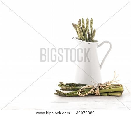 Fresh green asparagus in Jug on old wooden background