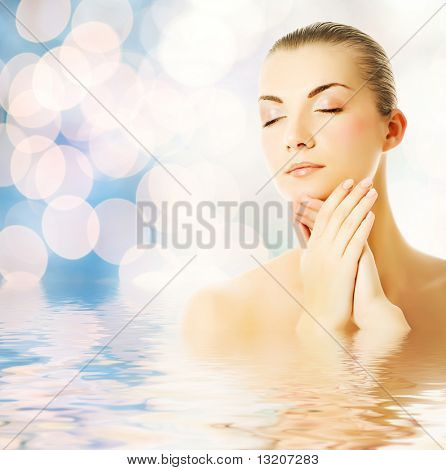 Bela jovem massageando o rosto com água