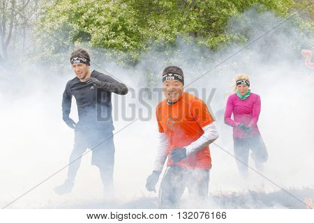 STOCKHOLM SWEDEN - MAY 14 2016: Colorful group of people running through fire and smoke in the obstacle race Tough Viking Event in Sweden May 14 2016