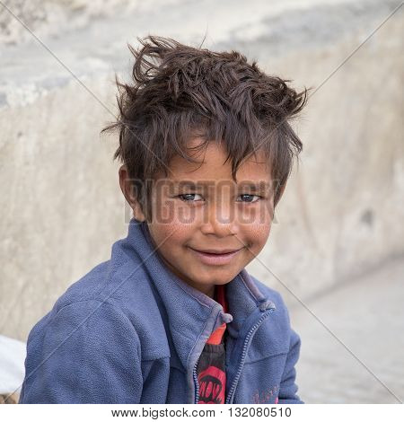 LEH INDIA - SEPTEMBER 08 2014: Unidentified beggar boy begs for money from a passerby in Leh. Poverty is a major issue in India