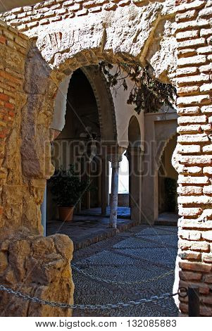 MALAGA, SPAIN - JULY 11, 2008 - View through an old arch doorway towards the ornate columns of Nasrid Palace entrances Malaga castle (Alcazaba de Malaga) Malaga Malaga Province Andalucia Spain Western Europe, July 11, 2008.