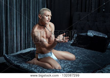 Metrosexual man playing on the bed in his neck dog collar.