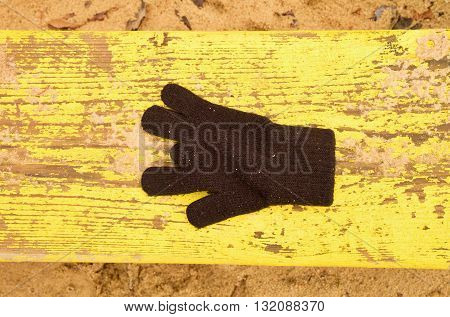 Lost Woolen Gloves On Yellow Bench. Sandy Gren Wooden Bench.  Sandbox With Dirty Sand In Kindergarde