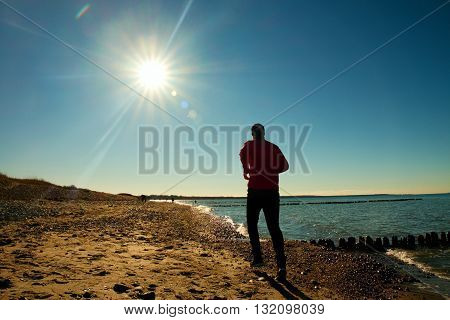 Runner  In Red Sportswer Running And Exercising On Stony Beach At Breakwater.