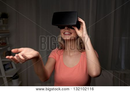technology, virtual reality, entertainment and people concept - happy young woman with virtual reality headset or 3d glasses playing game at home and holding something invisible