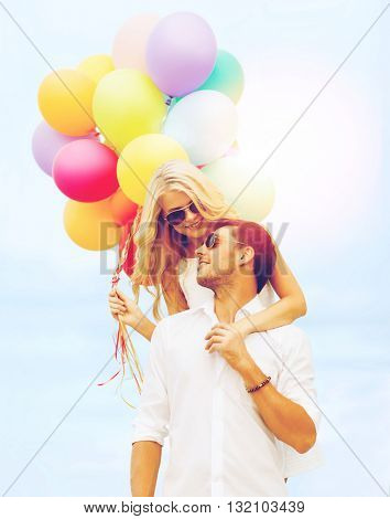 summer holidays, celebration and dating concept - couple in sunglases with colorful balloons over blue sky background
