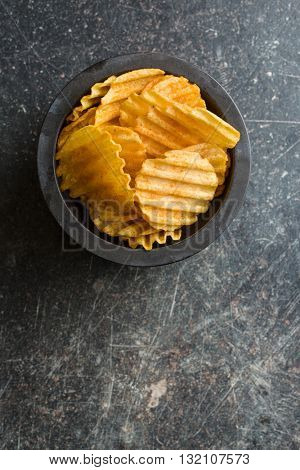 Crinkle cut potato chips on table. Tasty spicy potato chips.