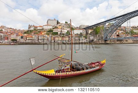 PORTO PORTUGAL - MAY 25 2016: Traditional Rabelo boat (port wine carrier) on Douro River in Porto Portugal. Dom Luis I Bridge and historical part of Porto city (UNESCO site) at the background