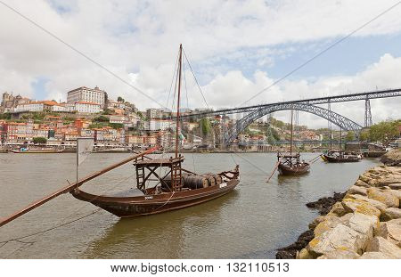 PORTO PORTUGAL - MAY 25 2016: Traditional Rabelo boats (port wine carrier) on Douro River in Porto Portugal. Dom Luis I Bridge and historical part of Porto city (UNESCO site) at the background