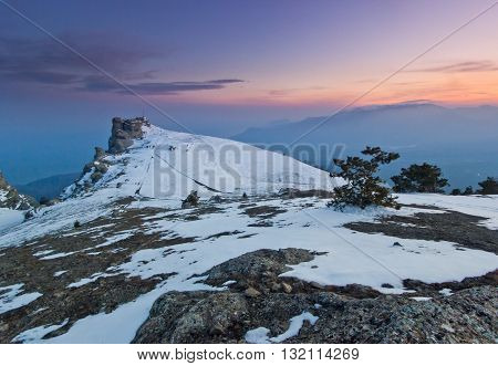 snow-covered mountains and rocks at purple sunset with clouds on sky