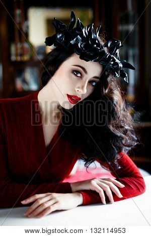 Beautiful model with a rad and black wreath of flowers on her head