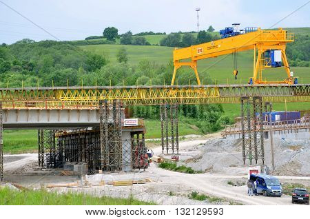 Ovciarsko, Slovakia - May 27, 2016: Yellow bridge crane on construction site of slovak D1 highway. Except for the crane there are some workers and cars.