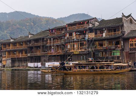 Hunan China 14 Nov 2011: Man Rowing Wooden Boat Along River Of Ancient Street.