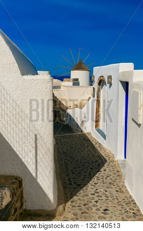 Picturesque view of empty streer, white and blue houses and windmill in Oia or Ia, island Santorini, Greece
