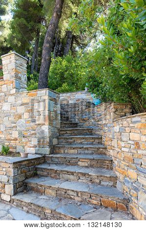Stairs of natural stone in yellow and blue tones leading into the woods, Pelion, Greece