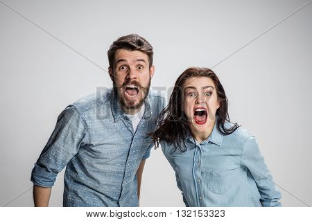The screaming man and woman looking at camera on gray background