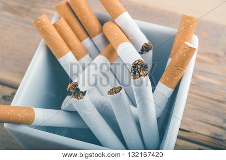 Quit Smoking - Broken Unsmoked Cigarettes In A White Ashtray With Blueish Filter