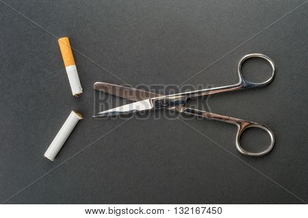 Quit Smoking - Scissors Cut A Cigarette Over A Dark Grey Background