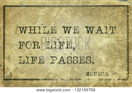 While we wait for life life passes - ancient Roman philosopher Seneca quote printed on grunge vintage cardboard