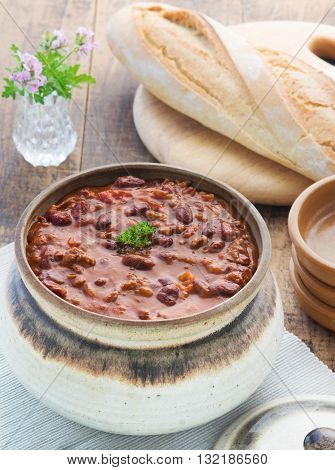 Top view of chilli con cane meal selective focus shot in a wooden table in a place setting with bread and plates