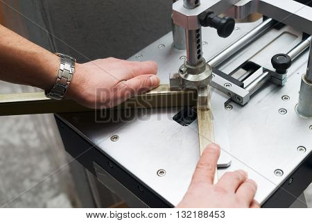 Craftsman working on frame in frameshop. Professional framer hand holding frame angle. Top view.