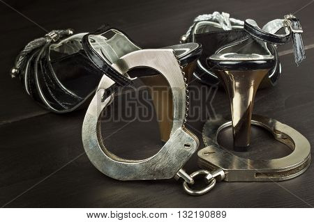 Metal handcuffs and women's shoes. The concept of sexual games. Violence against women, prostitution. Handcuffs for a sex game. Advertising sex shop.