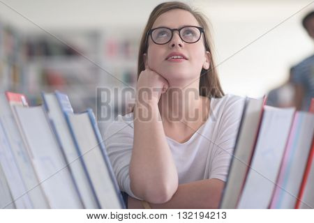 portrait of smart looking famale student girl  in collage school library,  selecting book to read from bookshelf