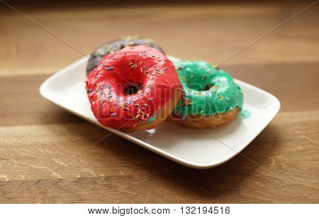 Colorful donuts on the plate, coconut topping. Top view.