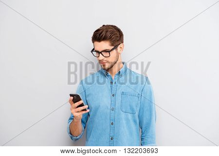 Portrait Of Young Guy In Spectacles Reading Message On Phone