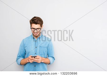 Happy Man In Glasses Typing Sms On Gray Background
