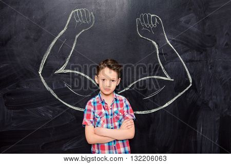 Powerful Young Schoolboy With Drawn Muscules On Blacboard