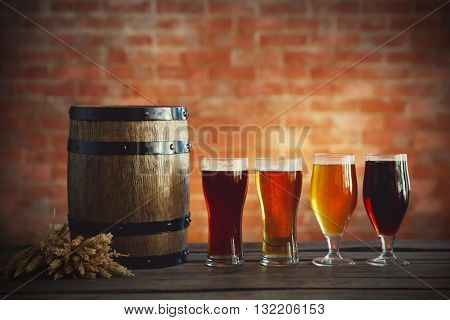 Glasses with different sorts of craft beer, wooden barrel and barley. Retro stylization