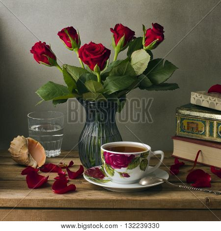 Red roses and cup of tea over wooden deck