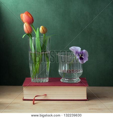 Still life with glass with tulips and glass with pansy.
